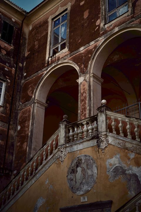 Verwittertes Gebäude mit Rundbögen, Fenstern und steinerner Balustrade