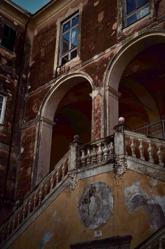 Verwittertes Gebäude mit Rundbögen, Fenstern und steinerner Balustrade