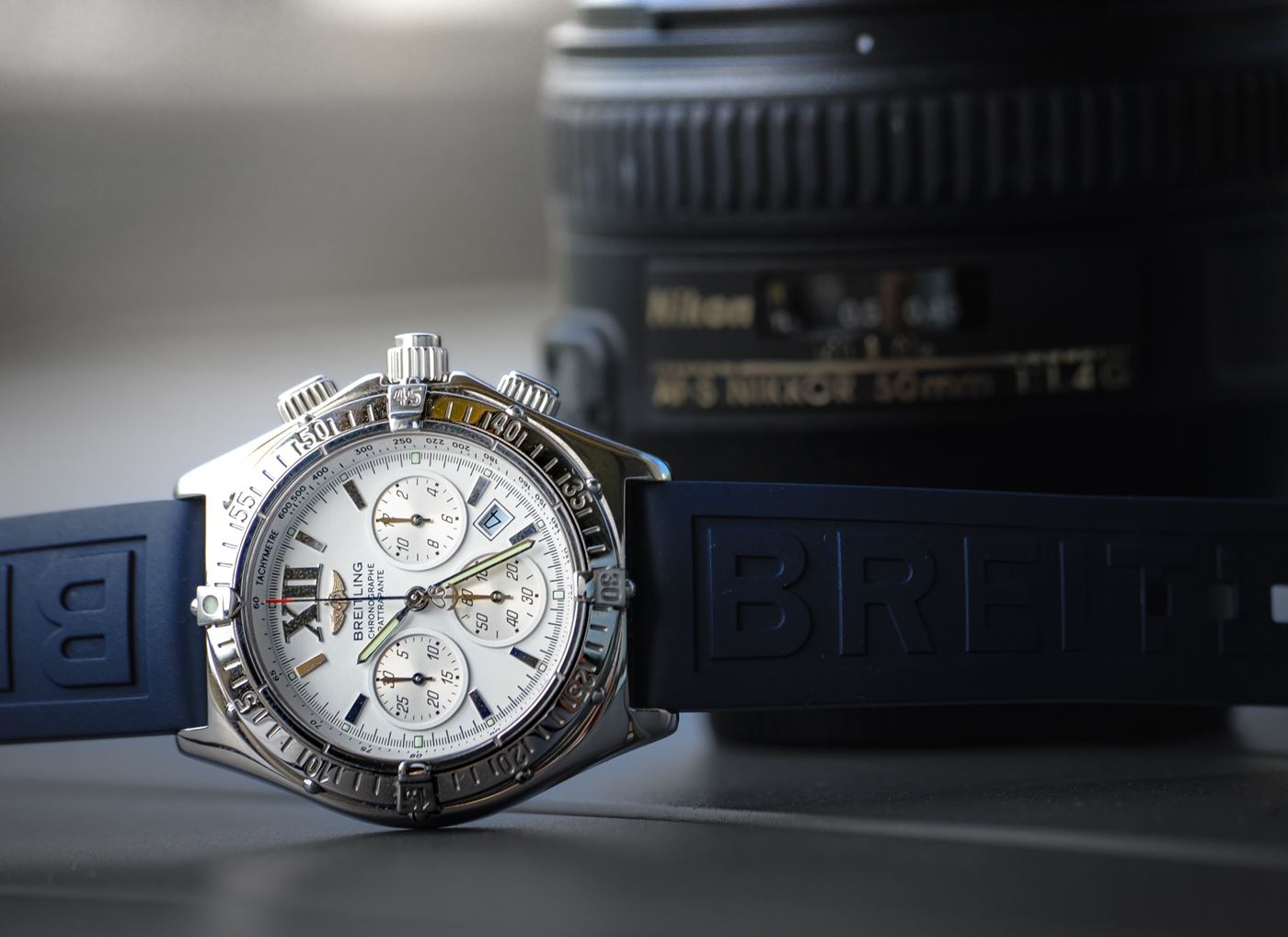 Breitling-Uhr vor einem Kameraobjektiv